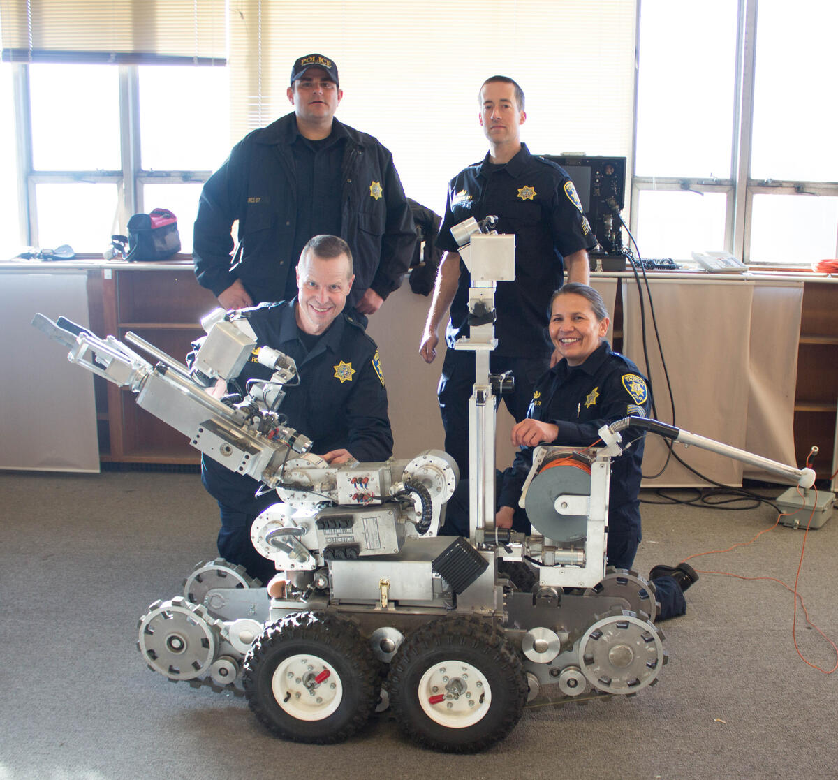 Four bomb squad officers around explosive ordnance robot